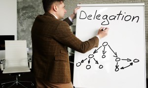 delegating in business mentor near whiteboard writing delegation and teaches delegate